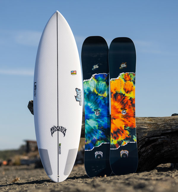 Three surfboards displayed on a beach, two colorful and one white.