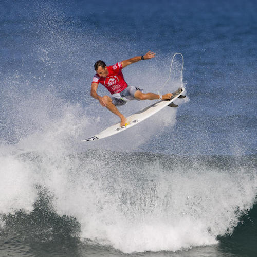 Surfer performing a jump over a wave.