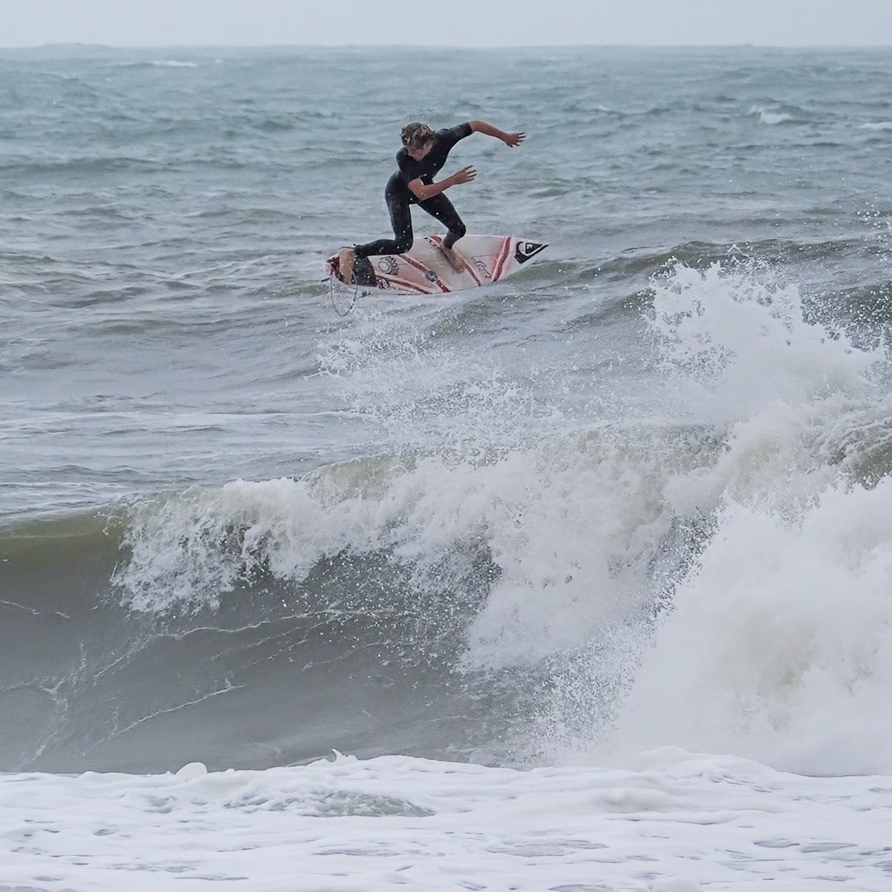 Surfer performing a maneuver on a wave in the ocean.