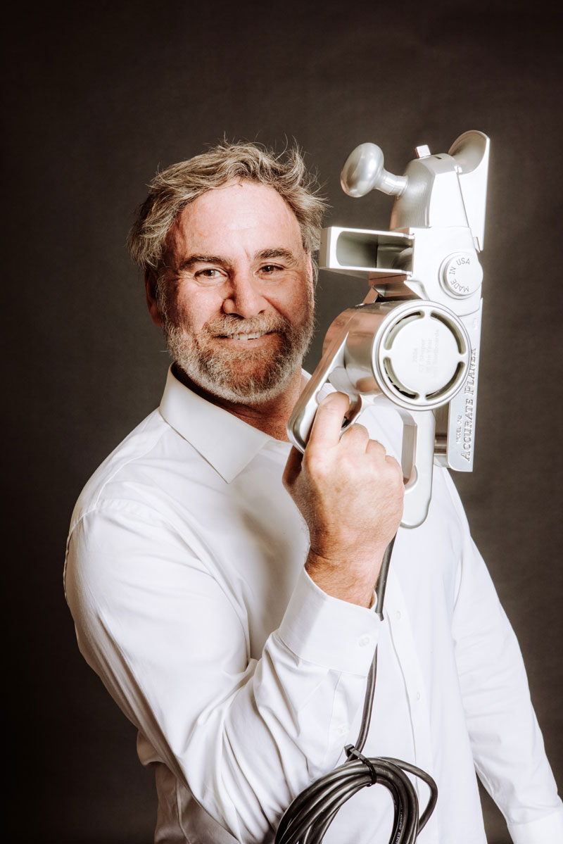 Man in a white shirt holding a vintage film projector.