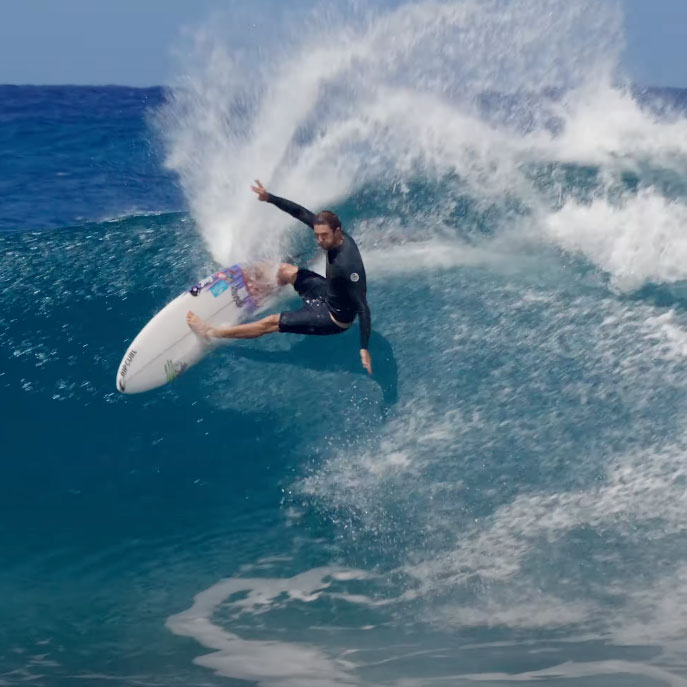 Surfer performing a maneuver on a wave in Hawaii.