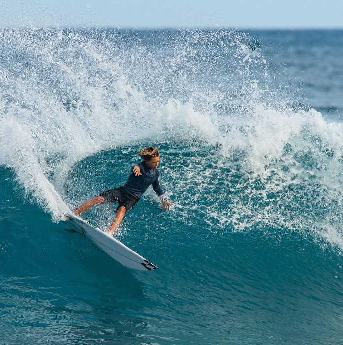 Young surfer riding a wave with splashing water.