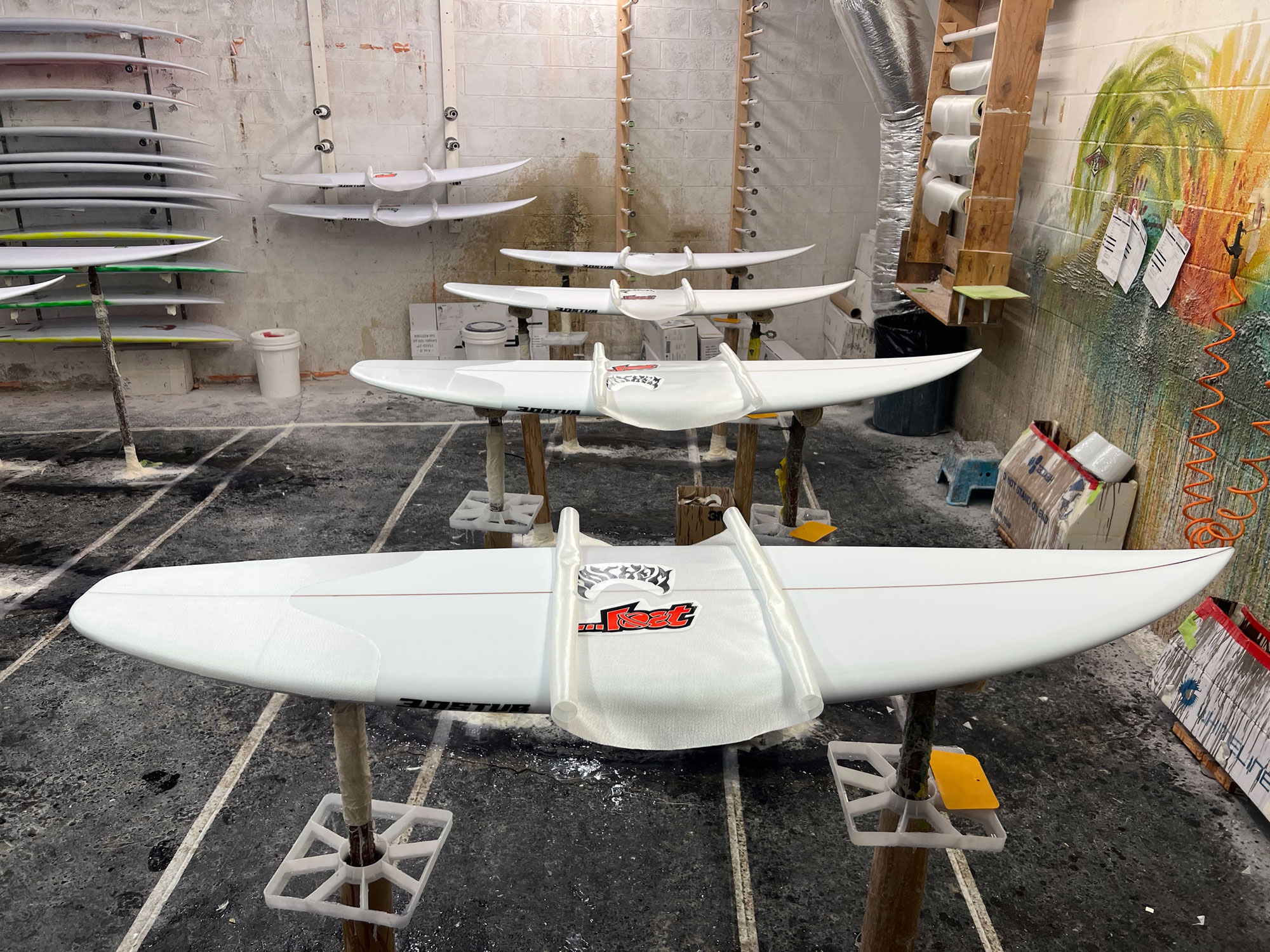 Custom surfboards in a workshop with tools and materials.