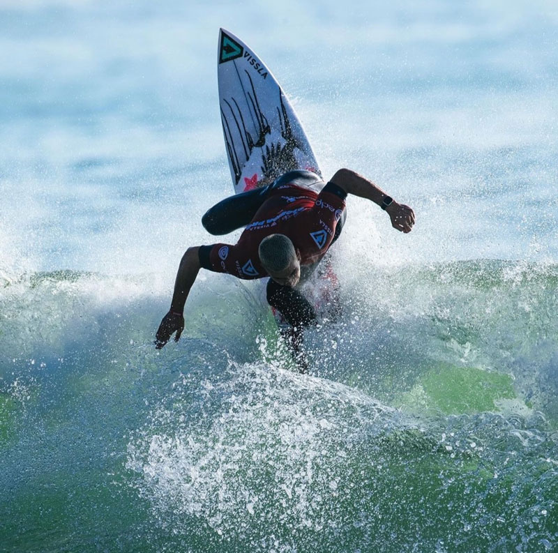 Surfer performing a maneuver on a wave, splashing water.