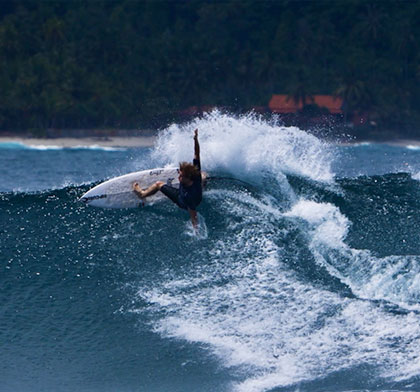 Surfer performing a maneuver on a large wave.
