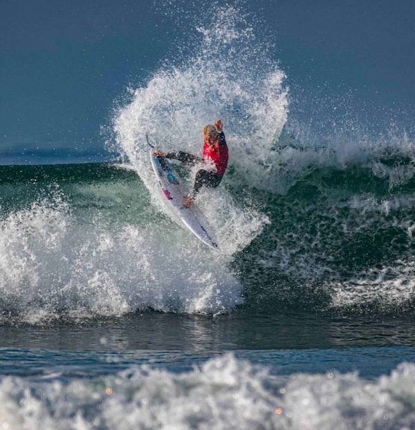 Surfer performing a maneuver on a large wave.