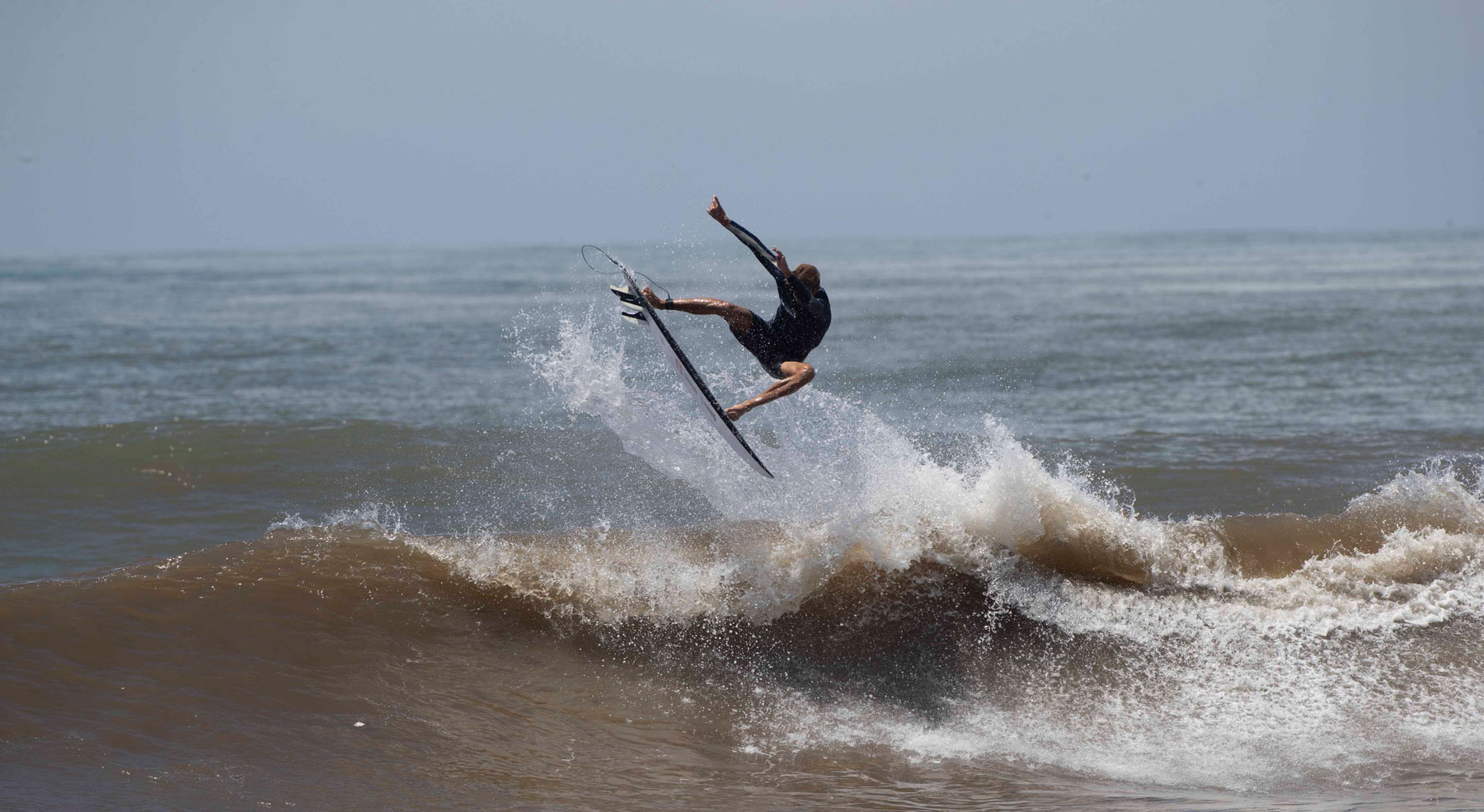 Surfer performing a jump over a wave in Bali.