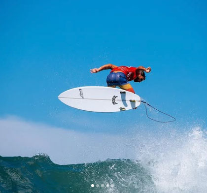 Surfer performing a jump above ocean waves.