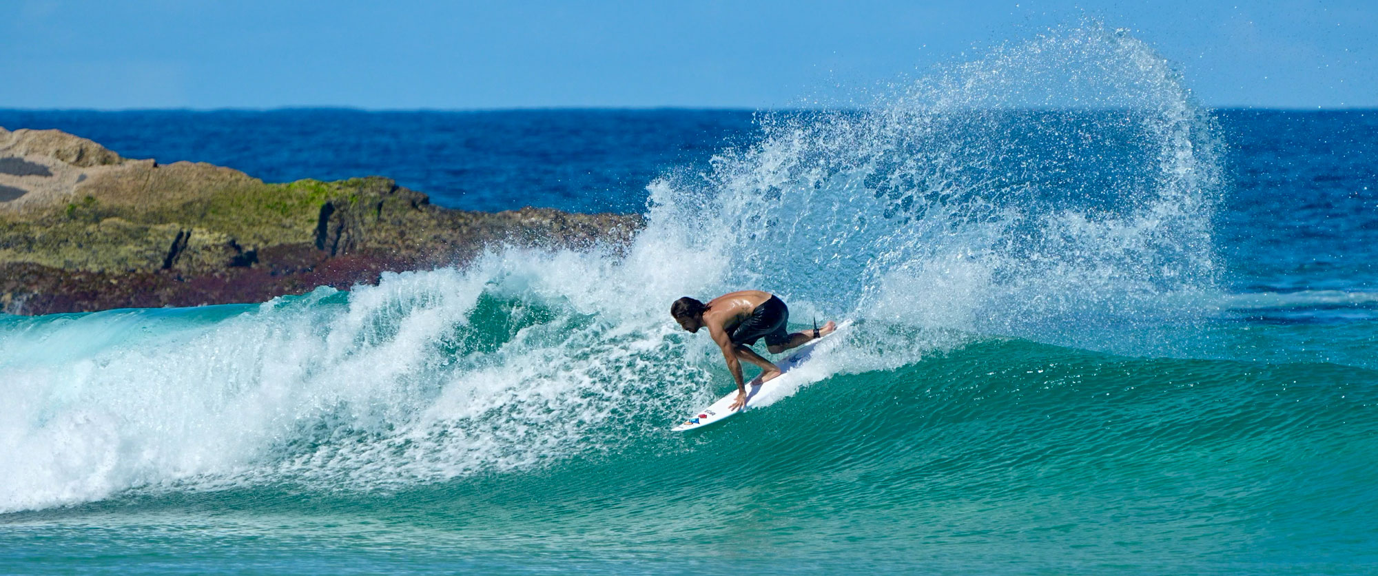 Surfer riding a wave with splashes in the ocean.