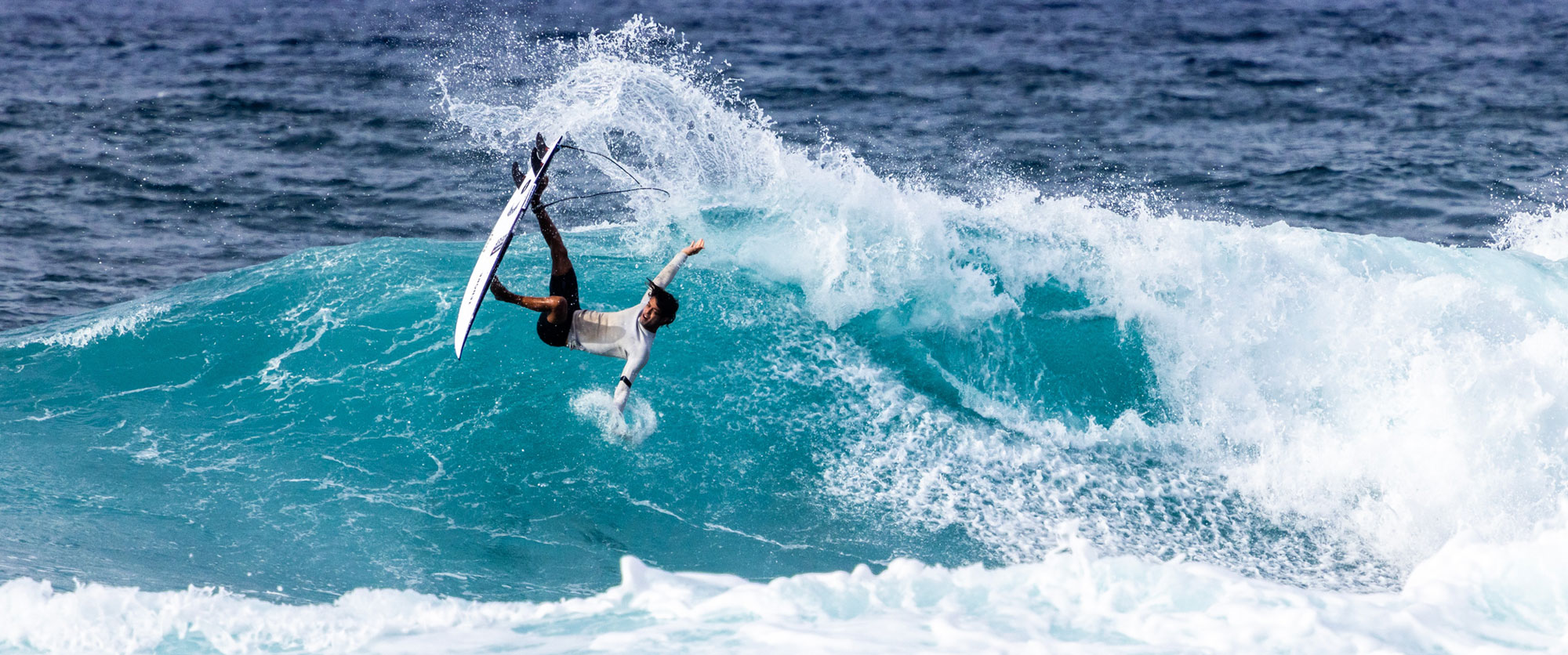 Surfer performing a trick on a large wave.