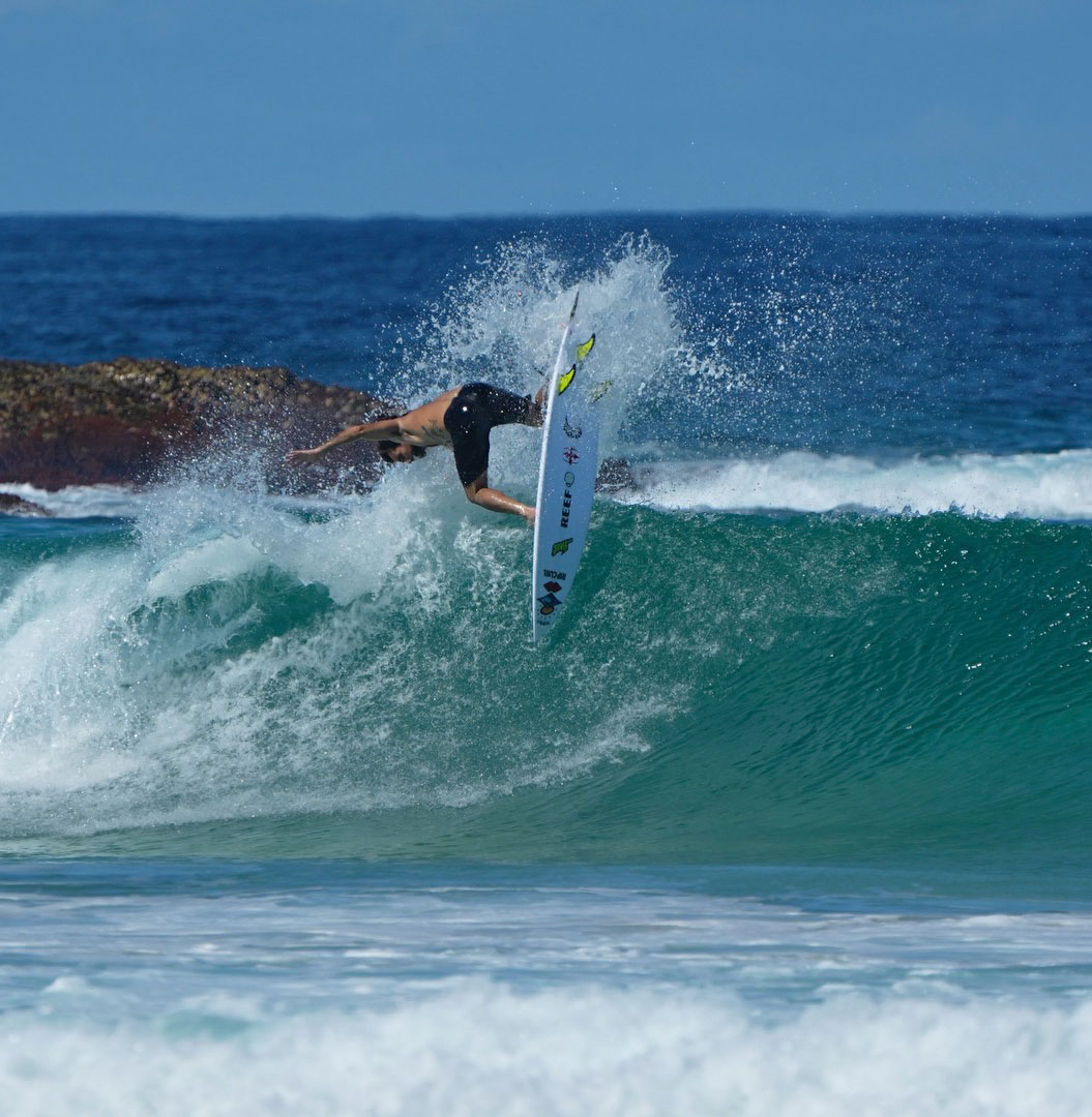 Surfer performing a maneuver on a wave in the ocean.