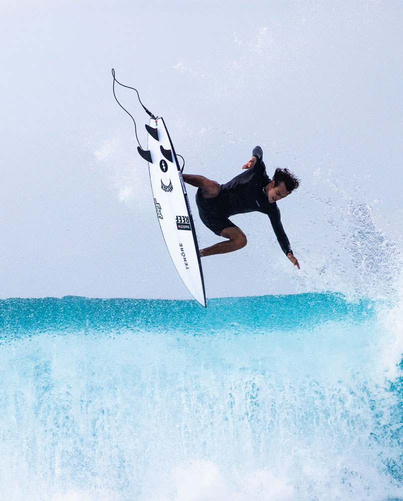 Surfer performing a jump above a wave.