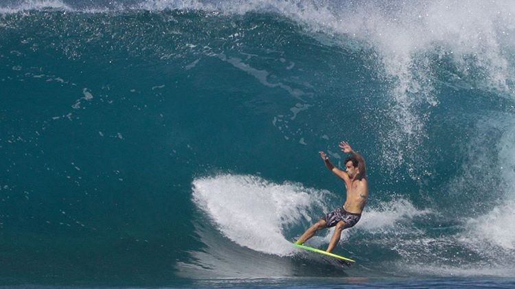 Surfer riding a large wave with spray in the air.