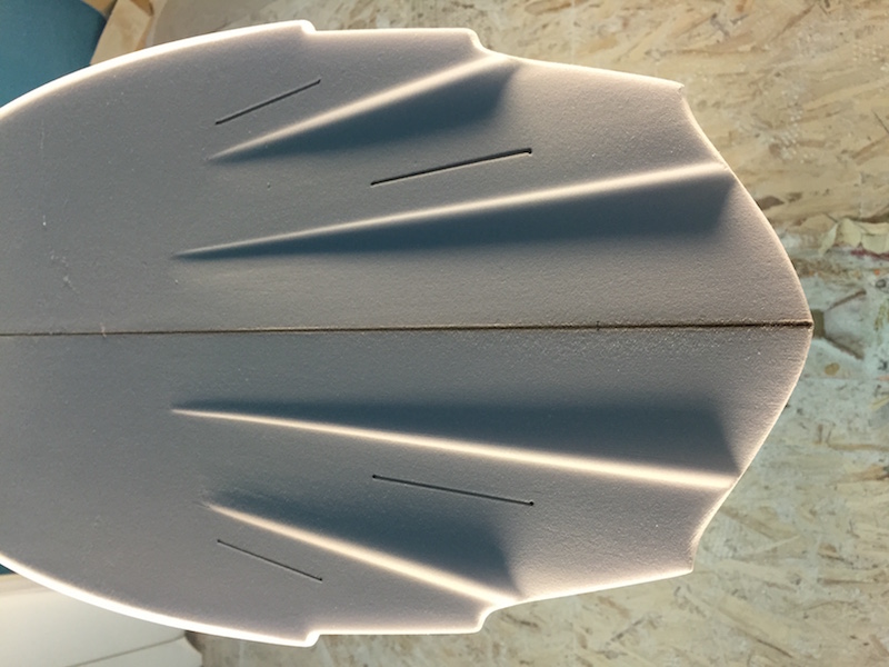Surfboard blank with shaped contours and markings.