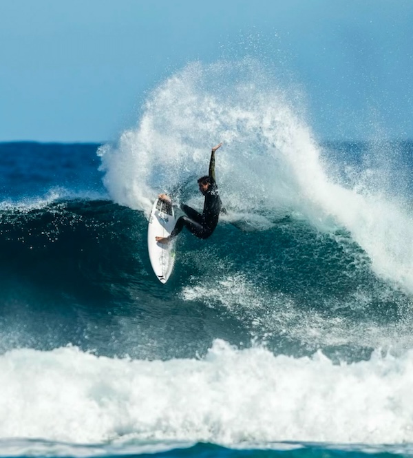 Surfer performing a maneuver on a large wave.