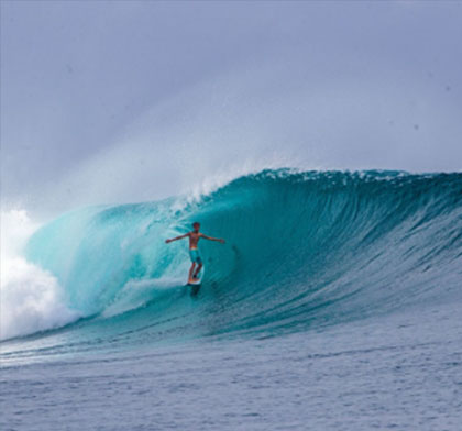 Surfer riding a large, turquoise wave.