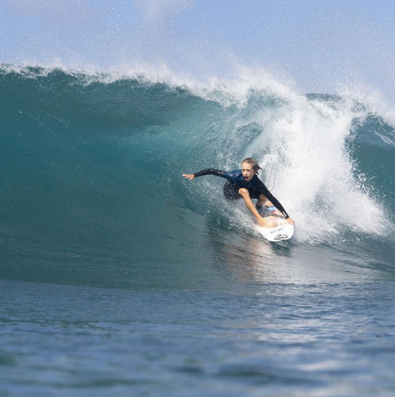 Surfer riding a wave, performing a maneuver on the board.