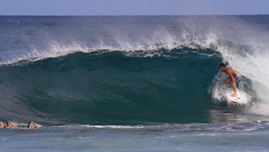 Surfer riding a wave in clear blue water.