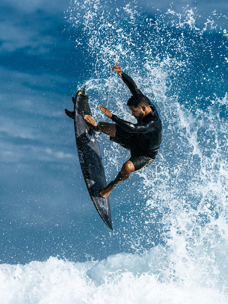Surfer performing a trick above crashing waves.