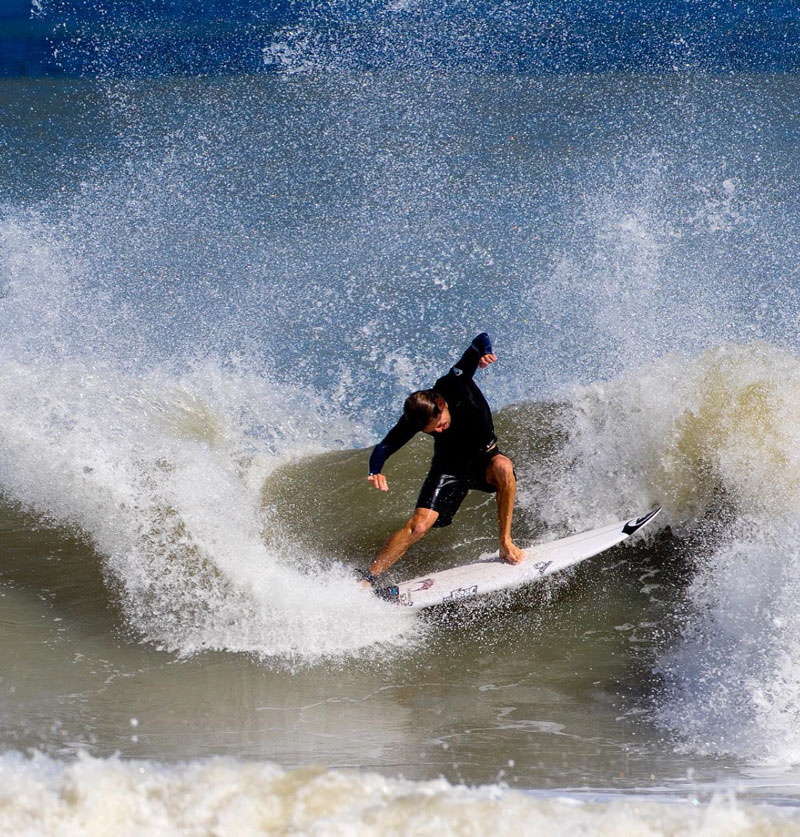 Surfer performing a maneuver on a wave with splashing water.