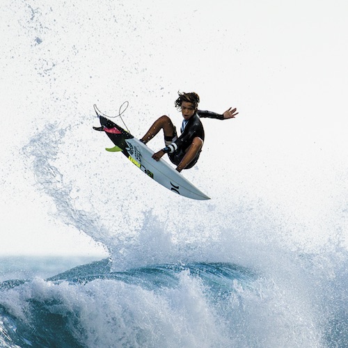 Surfer performing a jump above ocean waves.