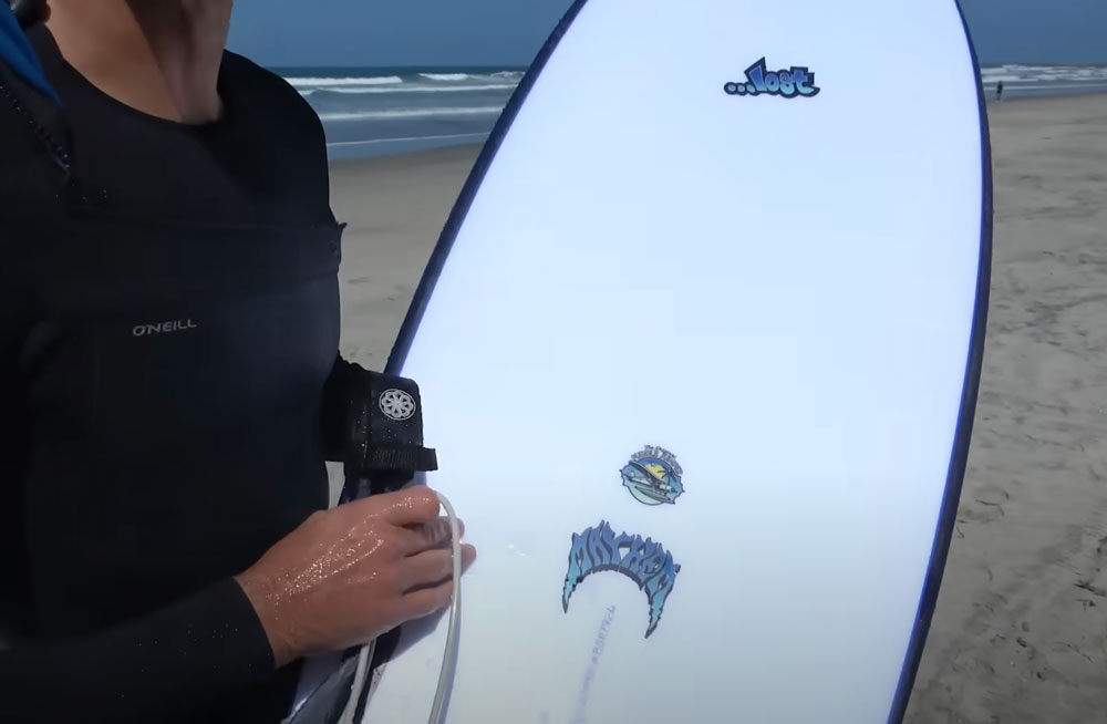 Person holding a surfboard on a beach.