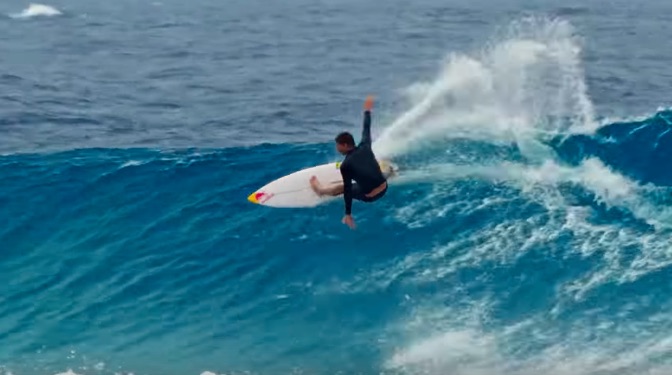 Surfer performing a maneuver on a large wave.