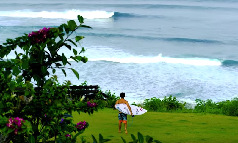 Surfer walking towards the ocean with a surfboard.