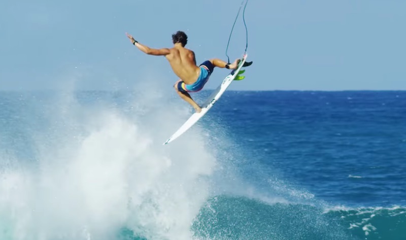 Surfer performing a jump above ocean waves.