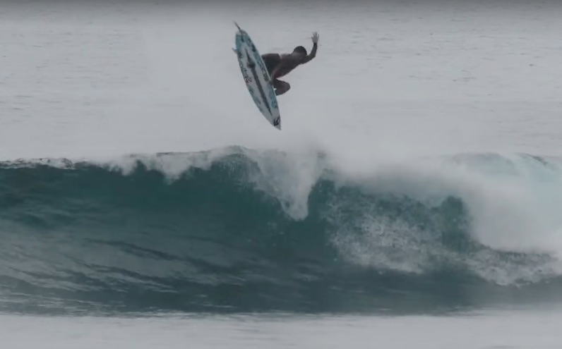 Surfer performing a jump above a wave.