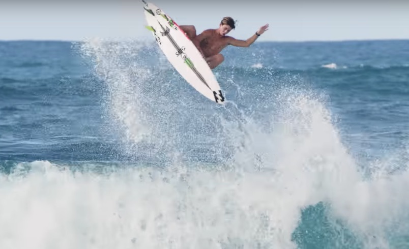 Surfer performing a jump over a wave in the ocean.