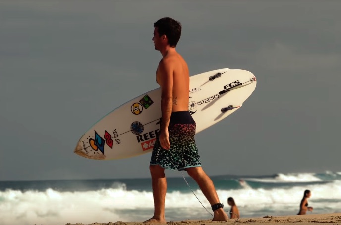 Surfer walking on the beach with a surfboard.