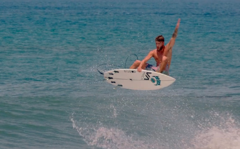 Surfer performing a jump over ocean waves.