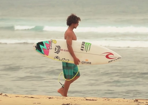 Surfer walking on the beach holding a surfboard.