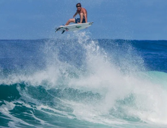 Surfer performing a jump above ocean waves.