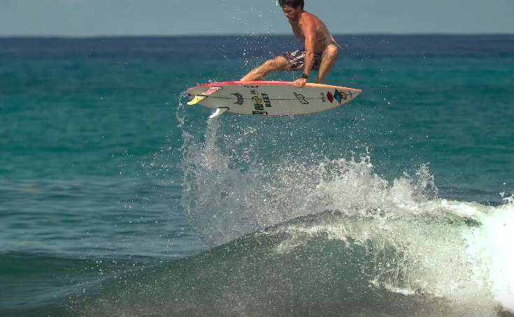 Surfer performing a jump over a wave in the ocean.