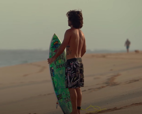 Surfer standing on the beach holding a surfboard.