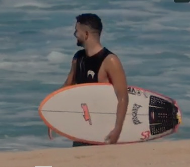 Surfer holding a board near the ocean shore.