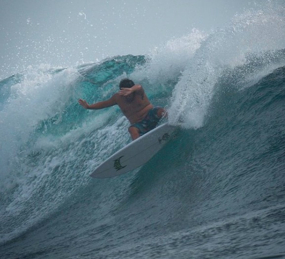 Surfer riding a large wave, spray and motion captured.