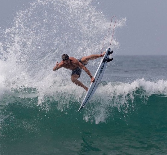 Surfer performing a trick on a wave, water splashing around.