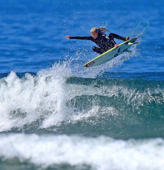 Surfer performing a jump over ocean waves.