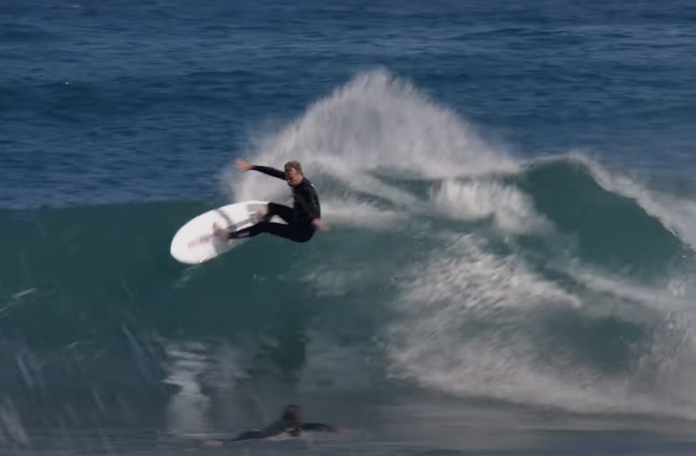 Surfer performing a maneuver on a wave in the ocean.