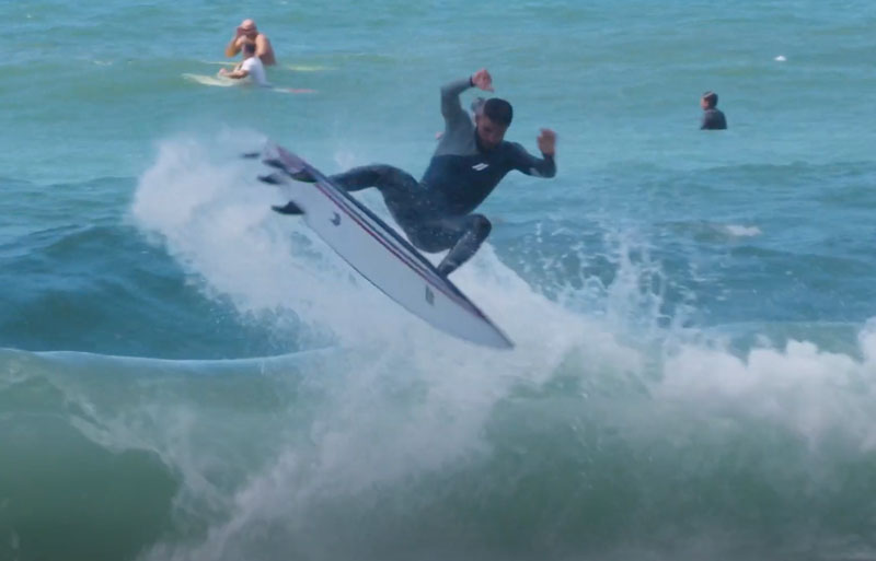 Surfer performing a jump over a wave in the ocean.