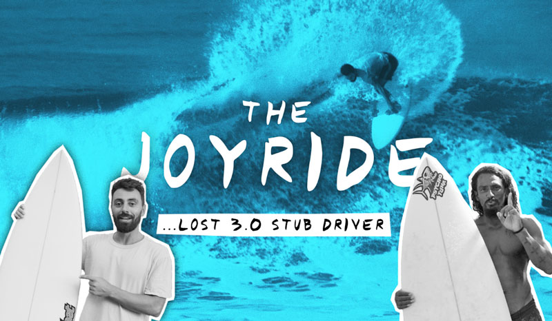 Two surfers holding boards with a wave in the background.