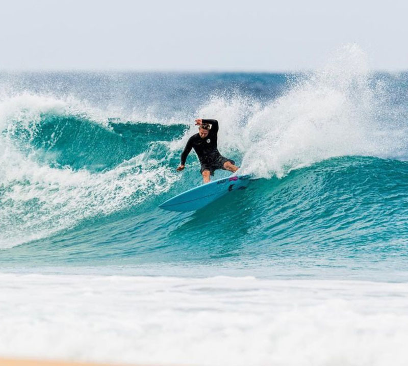 Surfer riding a wave on a blue surfboard.