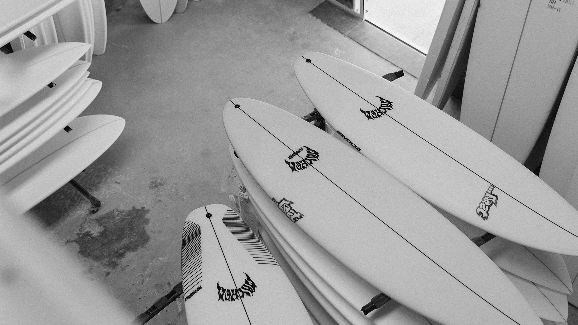 Stacked surfboards in a workshop, showcasing various designs.
