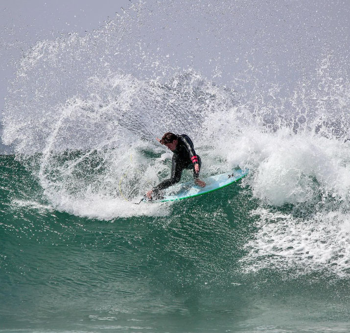 Surfer performing a maneuver on a wave, water splashing.