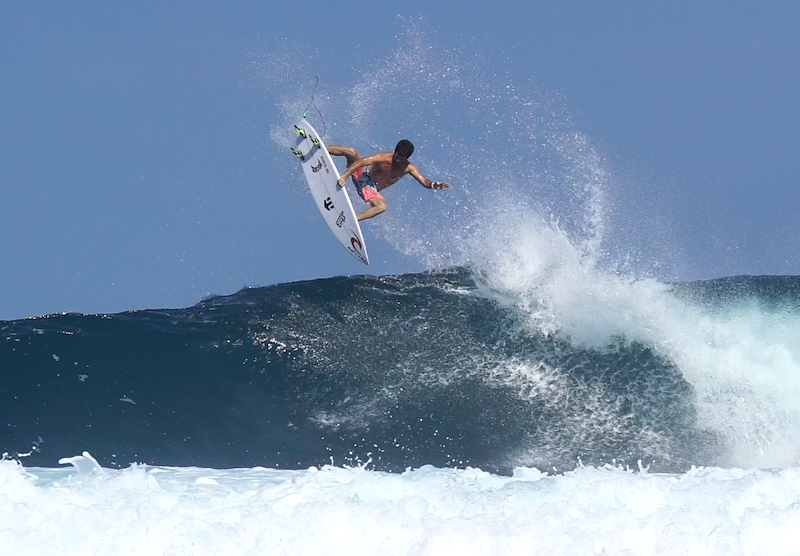Surfer performing an aerial maneuver above a wave.