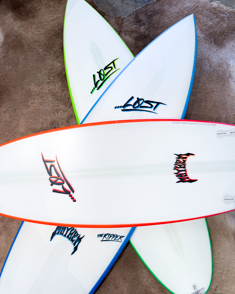 Three surfboards stacked on a textured surface.