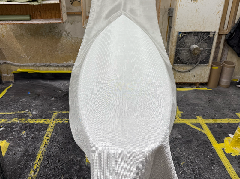 White fabric draped over a boat-shaped object in a workshop.